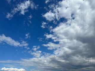 Blue sky with scattered fluffy white clouds and a touch of gray clouds.