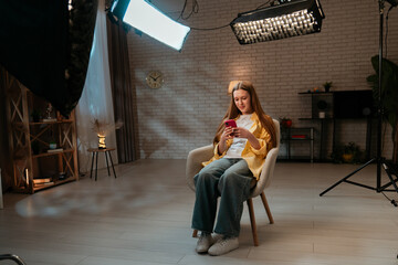 Young teenager girl spending evening time at home, girl sits in chair in the living room and...