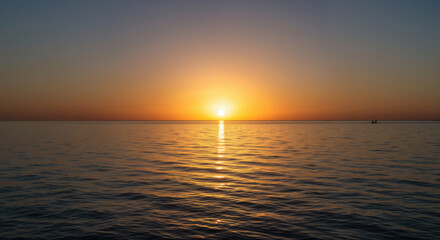 Obraz premium Golden sunset over calm sea with sun touching horizon and light reflection on water surface. Peaceful seascape for travel destinations, meditation retreats and wellness tourism marketing