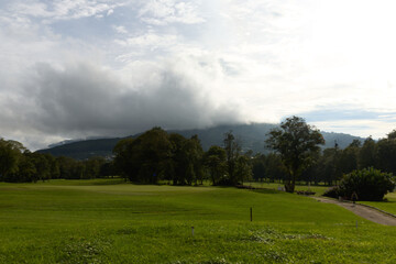 Serene golf course landscape with lush green grass, distant mountains, and cloudy sky ideal for relaxation and outdoor activities