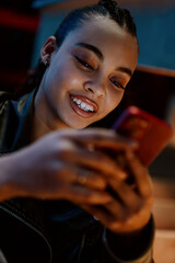 young woman enjoys convenience of online banking app while sitting outdoors in vibrant city at night. Female confidently manages her money transactions, staying secure and connected in digital world
