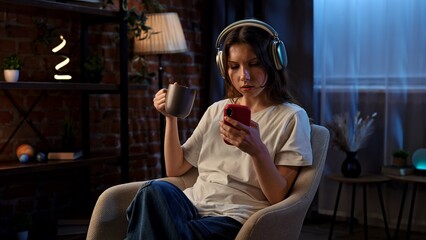 Woman Relaxing with Smartphone, Headphones, and Cup in Cozy Home Environment