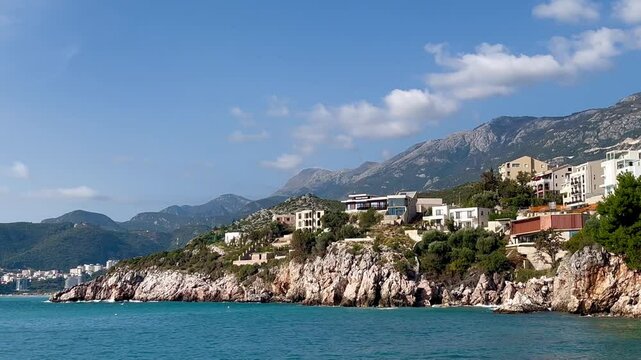 Modern villas on rocky Montenegro coastline near Milocer with dramatic mountain backdrop