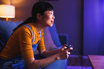 Woman relaxing at home late at night playing video games