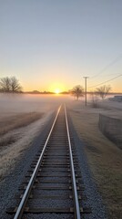 Obraz premium Railroad Tracks Disappearing into Fog at Sunrise Perspective View in Rural Landscape at Golden Hour