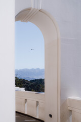 Scenic view of mountains and a flying helicopter framed by white architectural elements