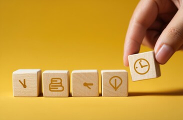 Prioritizing learning and time management.  A hand places a wooden block with a clock icon on a line of blocks with icons representing books, study, and location