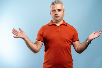 Confused mature man standing. I don't know. Portrait of mature confused man in orange t-shirt...