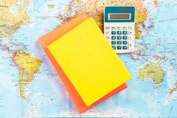 Notebook, calculator, notebook and textbooks on the world map. Concept of world economy and...