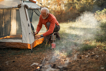Senior Man Camping in Scenic Nature Setting During Autumn