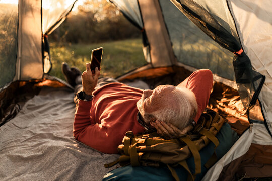 Senior Man Relaxing Inside Tent at Sunset in a Scenic Outdoor Setting