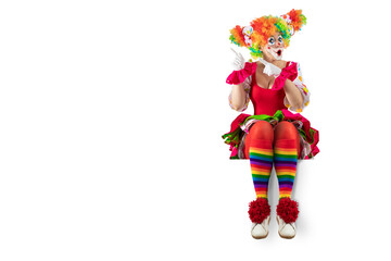 Suprised female clown pointing at blank template copy spase for advertising, posters, greetings, invitations. Entertainer as Joker in a suit and wig, with clown whiteface makeup.