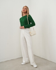 Woman posing in trendy outfit with bag in minimalistic indoor setting