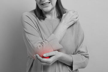 Arthritis. Senior woman suffering from pain in elbow, closeup. Black and white toning with red...