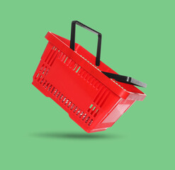 Red shopping basket in air on light green background