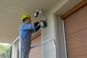 Image of an electrician on a scaffolding while assembling a video surveillance system. External electrical system of a house.