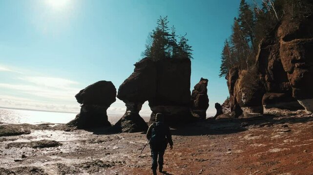 Slow-motion of a Hispanic man walking towards towering rock formations on a sunny winter day