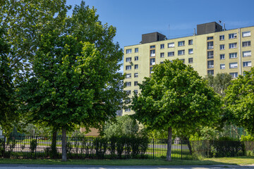 Multi-storey residential building surrounded by green trees.
