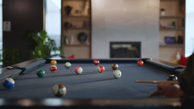 A group of friends gathers around a billiards table in a stylish lounge. The vivid balls are arranged in a relaxed setting, creating a fun environment for games.