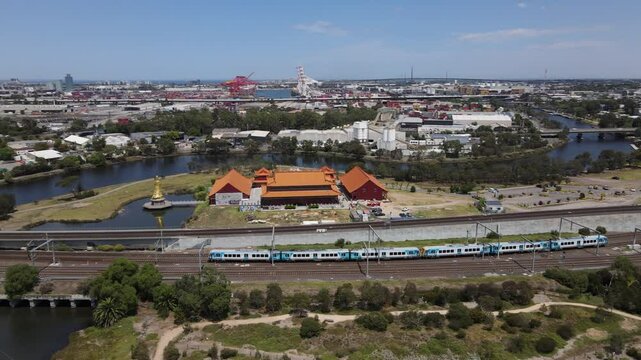 Aerial drone follows Metro train heading towards Melbourne city over nature reserve
