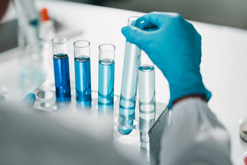 Medical science researcher handling chemical test tubes in a laboratory, analyzing samples with...