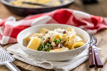 Typical Italian pasta Calamarata with bacon, fresh peas and parmesan cheese