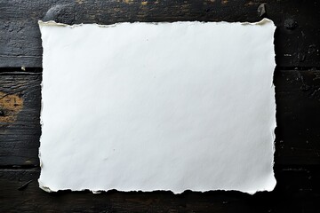 Blank sheet of off-white paper on dark wooden surface.  Frayed edges