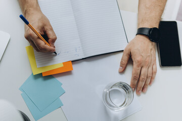 Close up, business man using mobile smart phone and and makes notes in a notebook. makes an...