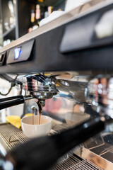 A close-up of an espresso machine pouring rich, dark coffee into a white cup. The image highlights the brewing process, fresh aroma, and professional equipment used in coffee preparation.