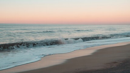 Fototapeta premium Gentle waves breaking on a sandy beach at sunset with pastel skies