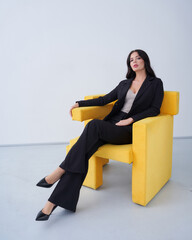 Confident businesswoman sitting in yellow armchair