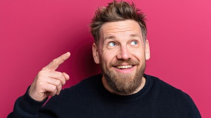 Fototapeta premium Cheerful Man with Beard Pointing Upwards Against a Vibrant Pink Background