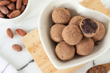 Chocolate energy balls with cocoa powder and dates in heart shape plate. Top view. Raw dessert or snack food concept.