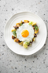 A delicious breakfast plate featuring a sunny-side-up egg with grilled mushrooms, corn, and potatoes, garnished with fresh greens. A vibrant and healthy meal perfect for a nutritious start to the day.