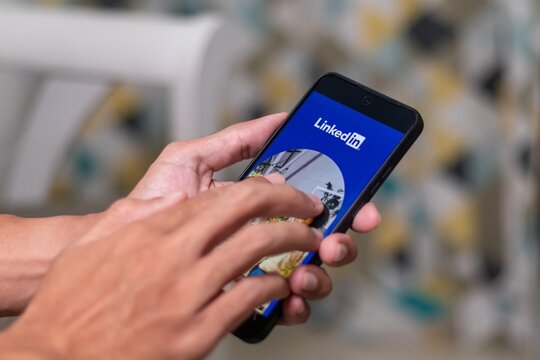 Jakarta, Indonesia - May 11, 2025: A man using Linkedin application on his smartphone to search for jobs
