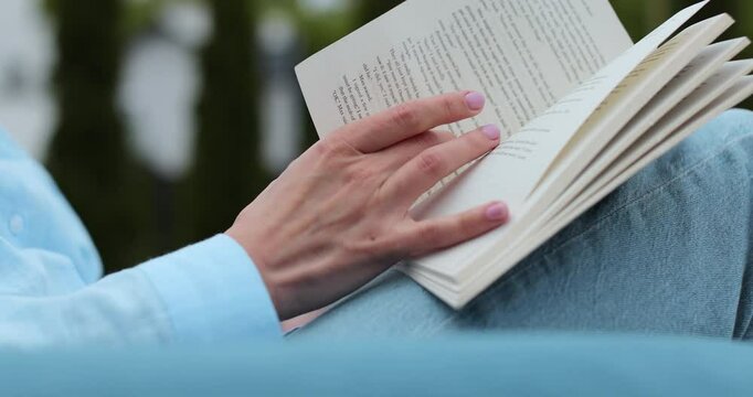 Close-up of a woman hand flipping to a new page outdoors.