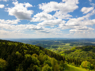 Aerial view of blooming summer landscape near Jizera Mountains with green hills, forests, meadows and picturesque villages, including views toward Jested mountain in Czech Republic