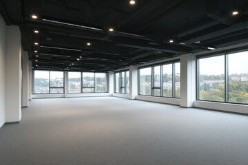 Empty office space with large windows gray carpet and dark ceiling.