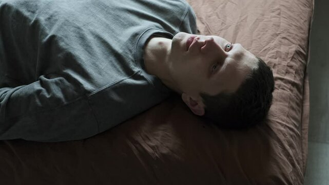 Dramatic man crying in despair. Portrait of emotional man lies on the bed and cries shedding a tear. Eye with tear drop. Depression or existential crisis