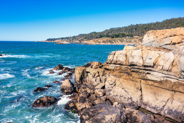 Coastal cliffs along California's Highway 1 in Northern California. Rugged ocean rocks, crashing waves, and a colorful sky create a breathtaking Pacific Coast landscape