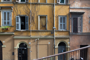 Charming vintage building exterior with weathered walls, climbing vines, and closed window...