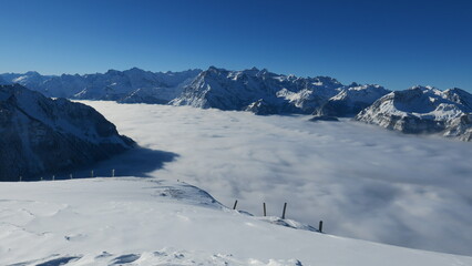 Fototapeta na wymiar Stunning panoramic view of snow-capped mountains rising above a sea of clouds. Perfect for winter, nature, and travel themes.