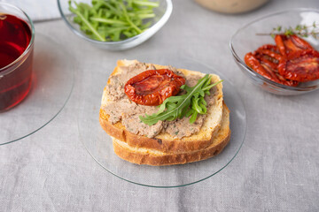 Chicken liver pate with wheat bread, arugula, sun-dried tomatoes and black tea. Homemade traditional rustic cuisine. Breakfast or snack option. Selective focus, close-up.
