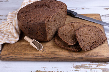 Rye Borodino (Borodinskiy) bread with a crispy crust on a wooden board, cut into slices. Homemade...