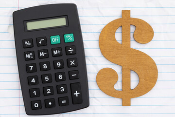 Cost of tuition with calculator and gold dollar symbol with wrinkled ruled loose leaf paper