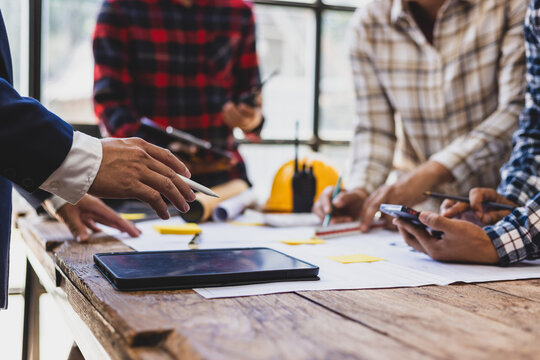 Team of architects and engineers working on construction project. Architect and engineer are using pencil, ruler on table with blueprint to discuss construction project. Construction design planning.