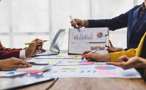 Business people analyzing financial statistics working together in office. Business professionals are working together in office, analyzing financial statistics and data on chart and graph. - Powered by Adobe