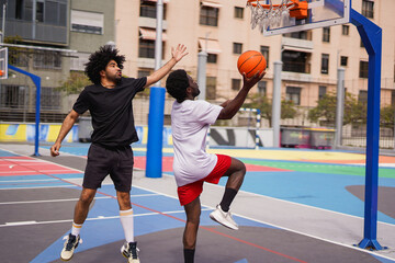 African men playing basketball in the city during summer time - Sport, urban lifestyle and young...