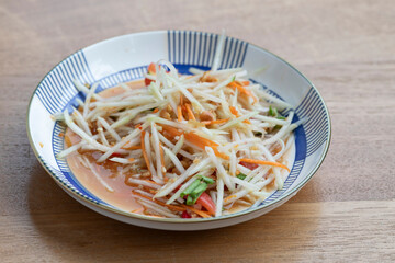 Papaya salad in dish on wooden table