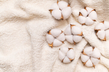 Cotton terry towels in neutral colors with cotton flowers close-up. Natural eco-friendly fluffy material for hygiene, spa, bath procedures. Towel mockup top view flat lay